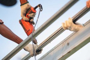 man worker uses a power drill to attach a clip